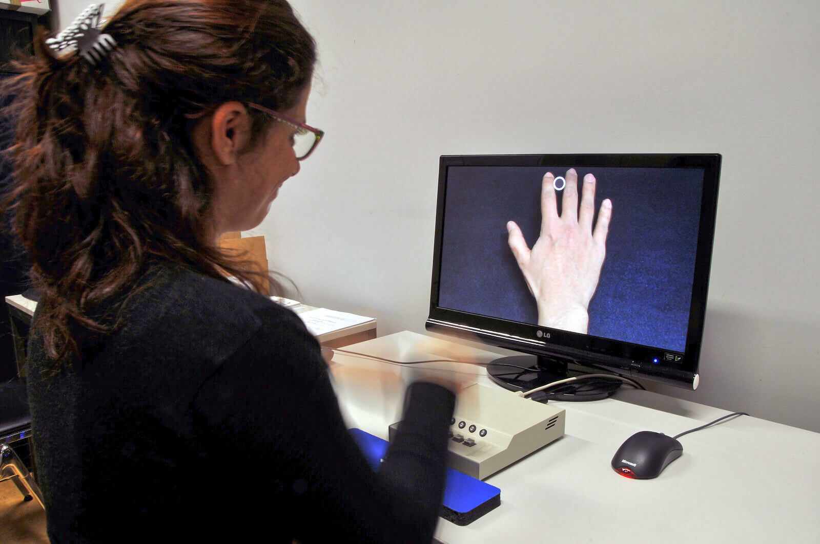 woman looking at her own hand on a monitor